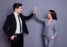 Profile side photo of cheerful businesspeople with wavy curly brunet, hairstyle giving high five wearing black jacket blazer isolated over gray background