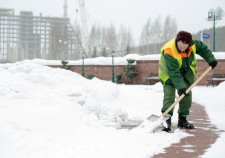 Woman worker in uniform shoveling snow after a storm