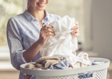 Cropped image of beautiful young woman is smiling while doing laundry at home