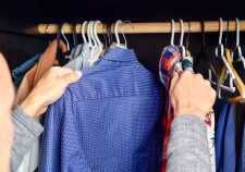 closeup of a young caucasian man choosing a shirt from a clothes rack