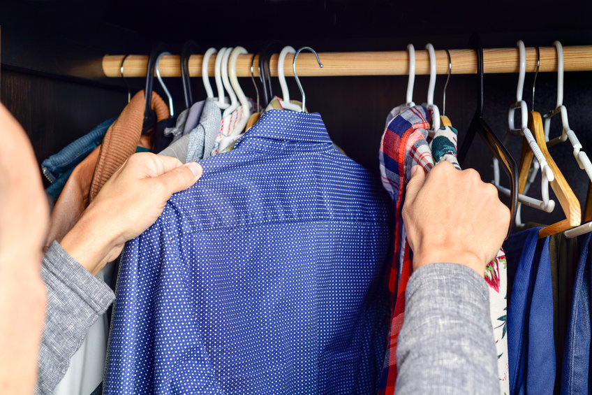 closeup of a young caucasian man choosing a shirt from a clothes rack