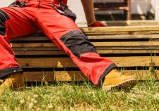 Unrecognizable person on construction site wearing protective worker red black pants trousers