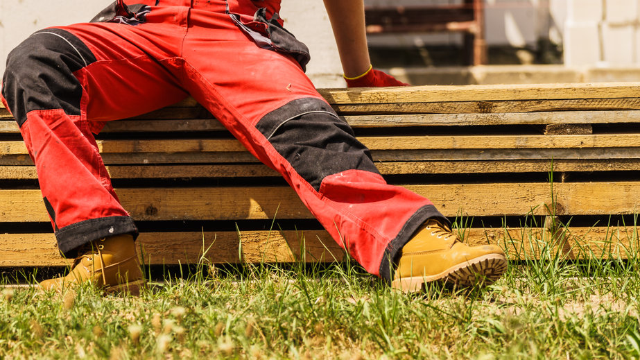 Unrecognizable person on construction site wearing protective worker red black pants trousers