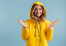 Image of joyful woman 20s wearing yellow raincoat looking at camera isolated over blue background